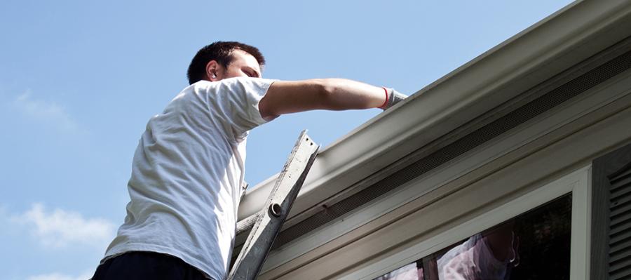 Mann som st&aring;r i stige og sjekker taket